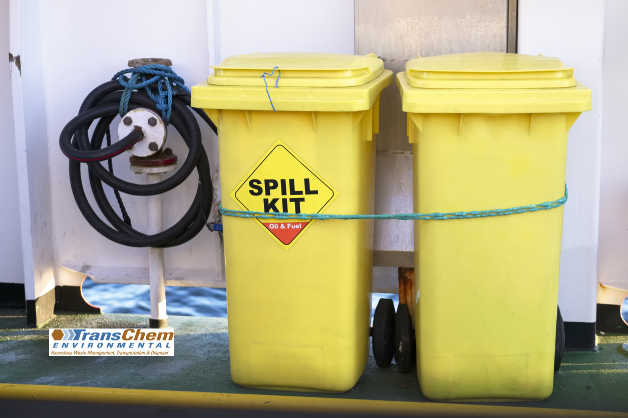 Yellow hazmat bins & spill kits tied against a wall for use if needed.